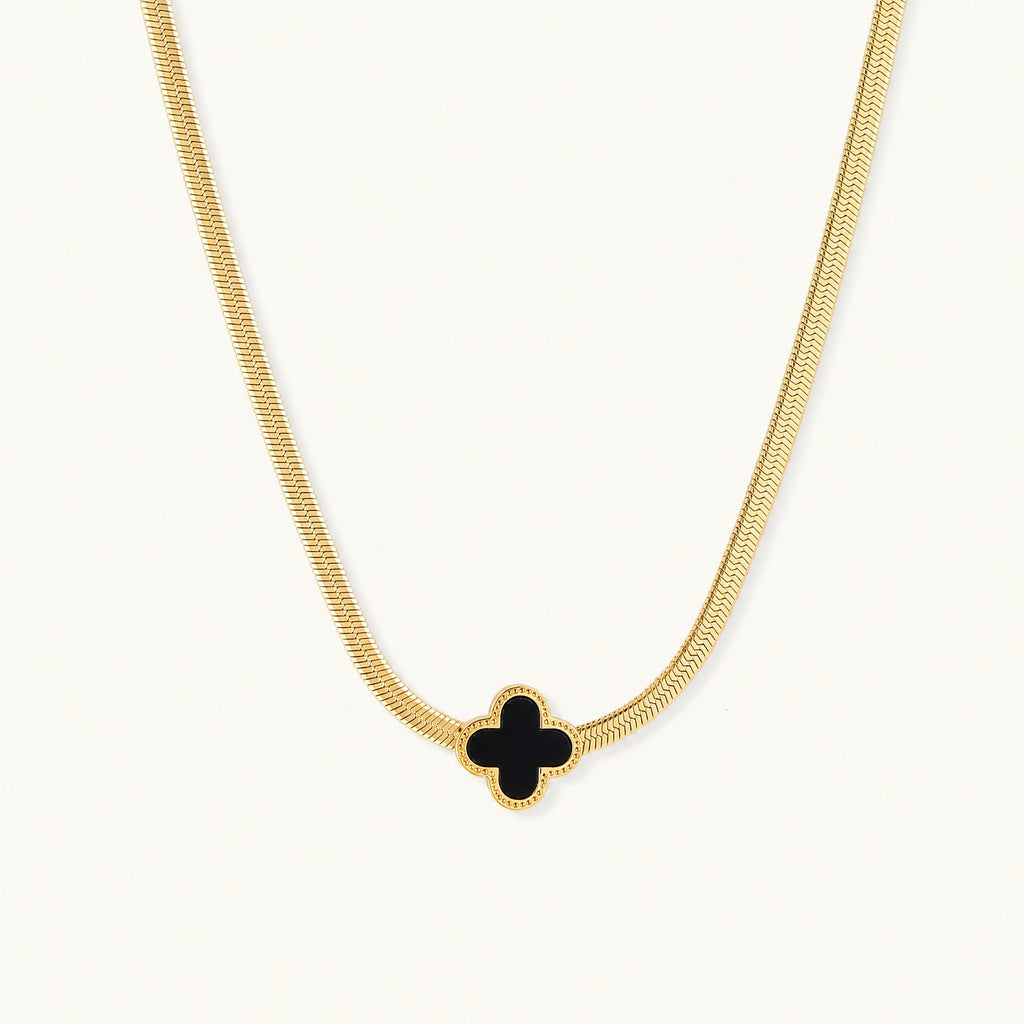 Dainty 18K gold-plated herringbone chain necklace with black enamel quatrefoil clover pendant on white background