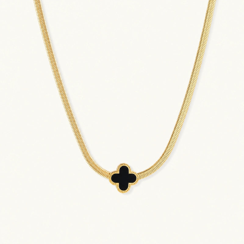 Dainty 18K gold-plated herringbone chain necklace with black enamel quatrefoil clover pendant on white background