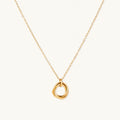 Delicate gold-plated necklace with three interlocking circle rings forming a minimalist knot pendant on cream background