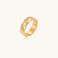 Close-up of an 18K gold-plated twisted band ring with dimensional braided pattern on cream background.