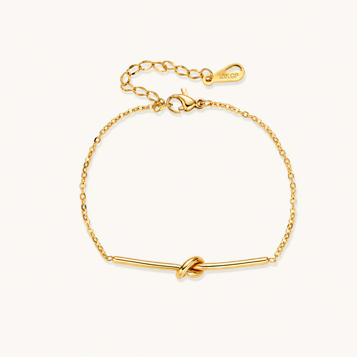Delicate gold chain bracelet with minimalist bar and centered knot detail on cream background