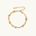 Three-strand gold-plated bracelet with clustered ball beads and adjustable clasp on cream background