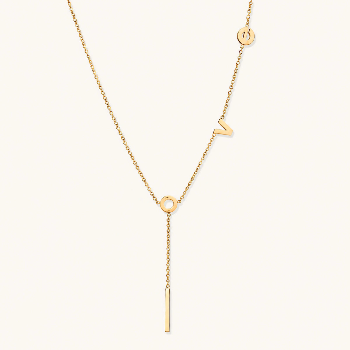 Gold Y-shaped necklace with L-O-V-E letter charms and vertical bar pendant on delicate chain against cream background