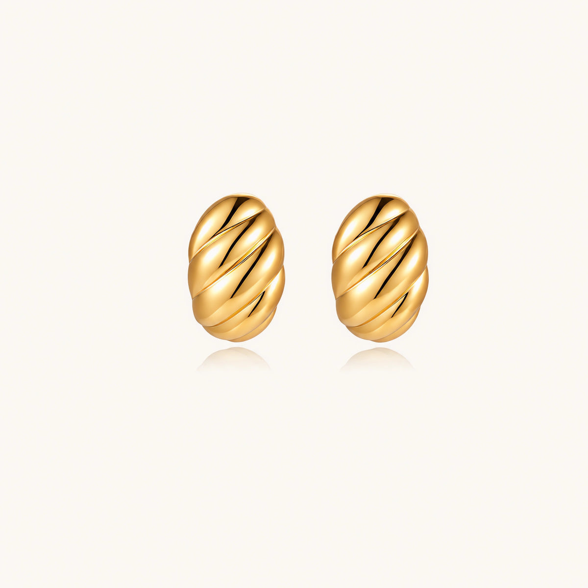 Chunky gold twisted rope huggie hoops with diagonal grooves and high-polish finish on cream background