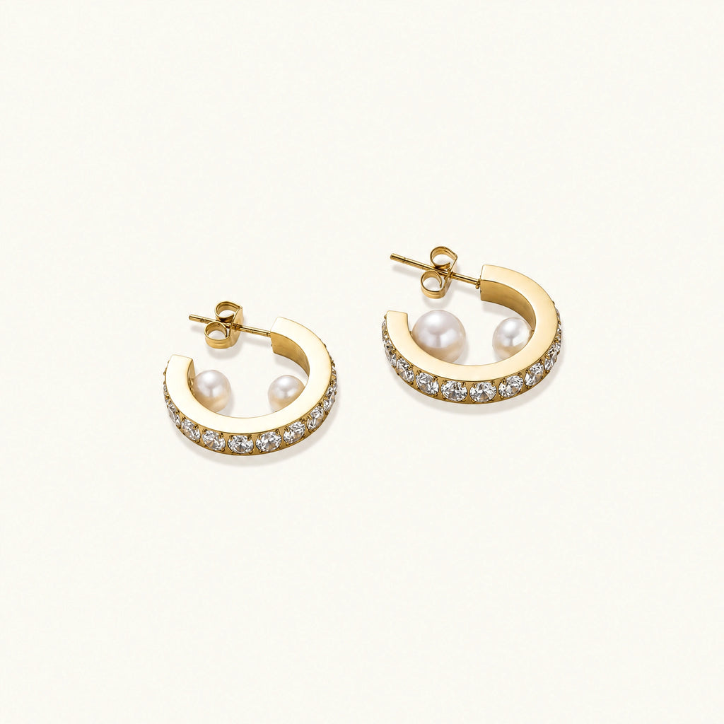 Gold pavé hoop earrings with two freshwater pearls nestled inside the curved design, featuring crystal-studded outer edge.
