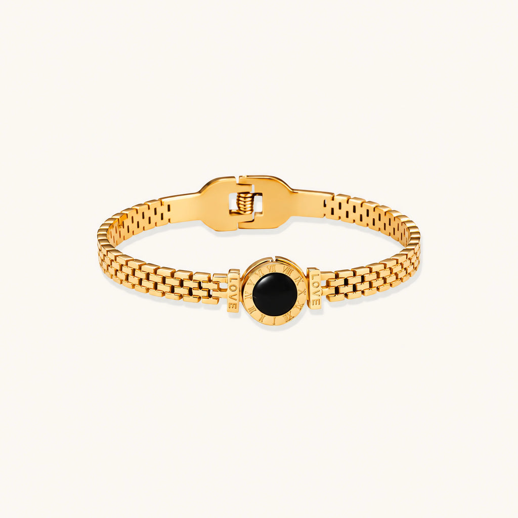 Gold mesh bracelet with circular black mother of pearl medallion featuring Roman numeral engravings and hinged clasp