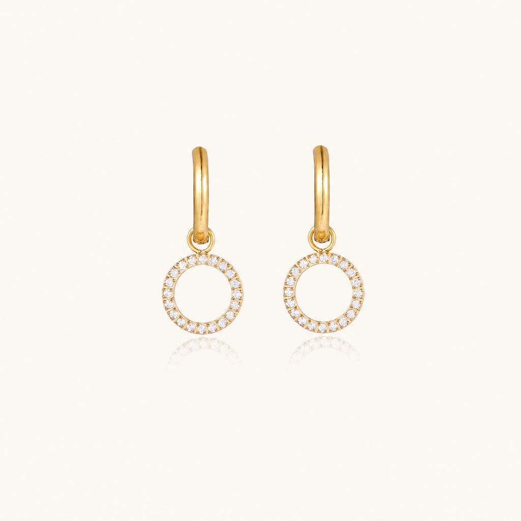 Gold-plated huggie hoop earrings with CZ-studded open circle charms on beige background