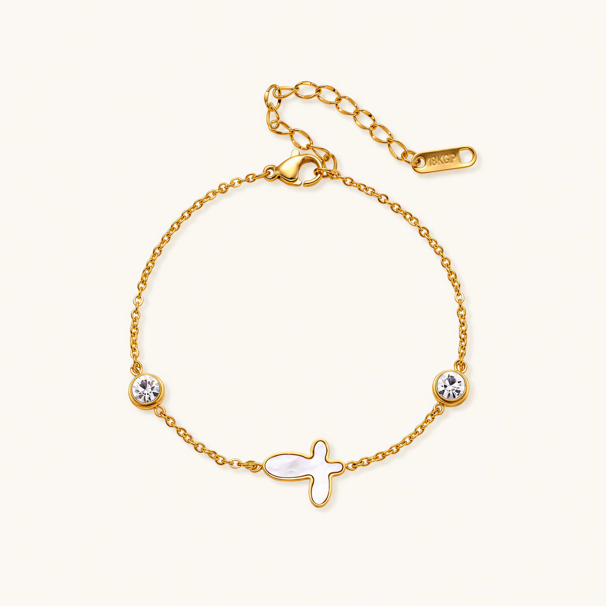 Gold chain bracelet with white mother of pearl butterfly pendant and two bezel-set crystals on cream background