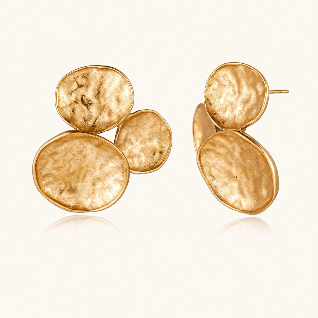 Three hammered gold discs clustered together forming organic statement earrings with textured surfaces