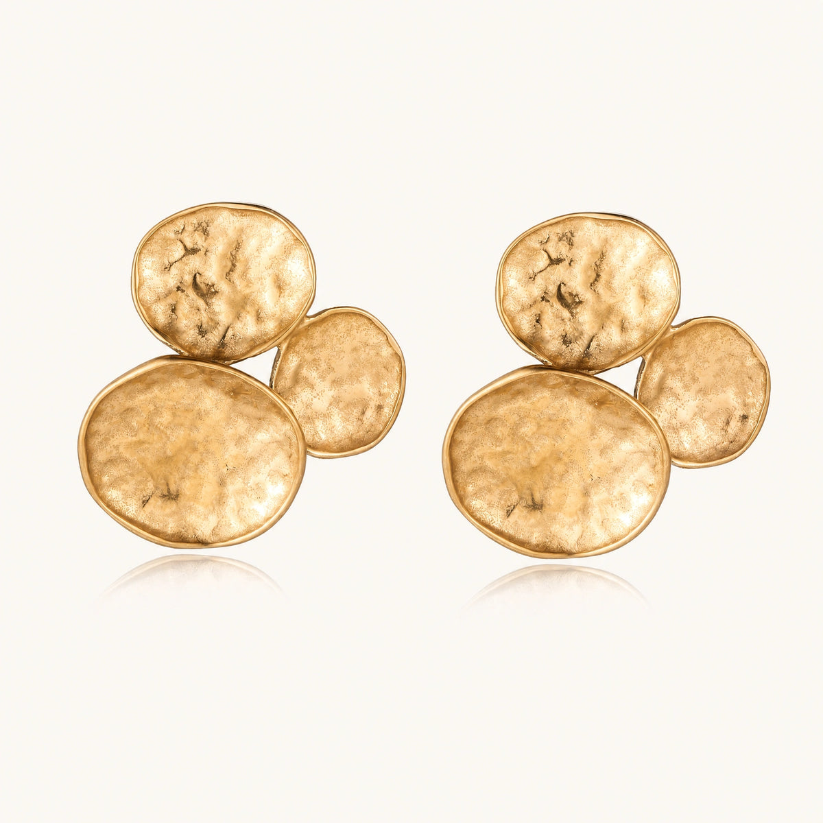 Three hammered gold discs clustered together forming organic statement earrings with textured surfaces