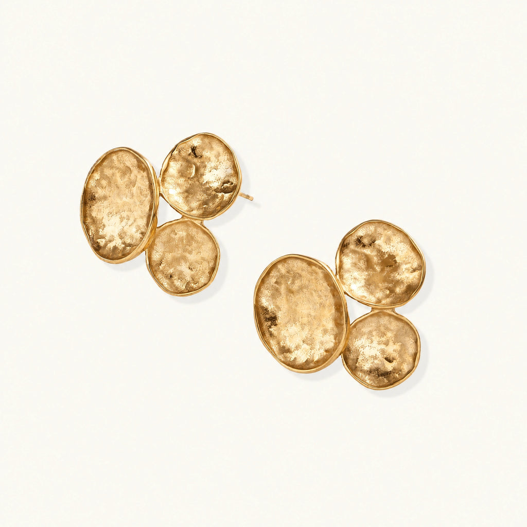 Three hammered gold discs clustered together forming organic statement earrings with textured surfaces