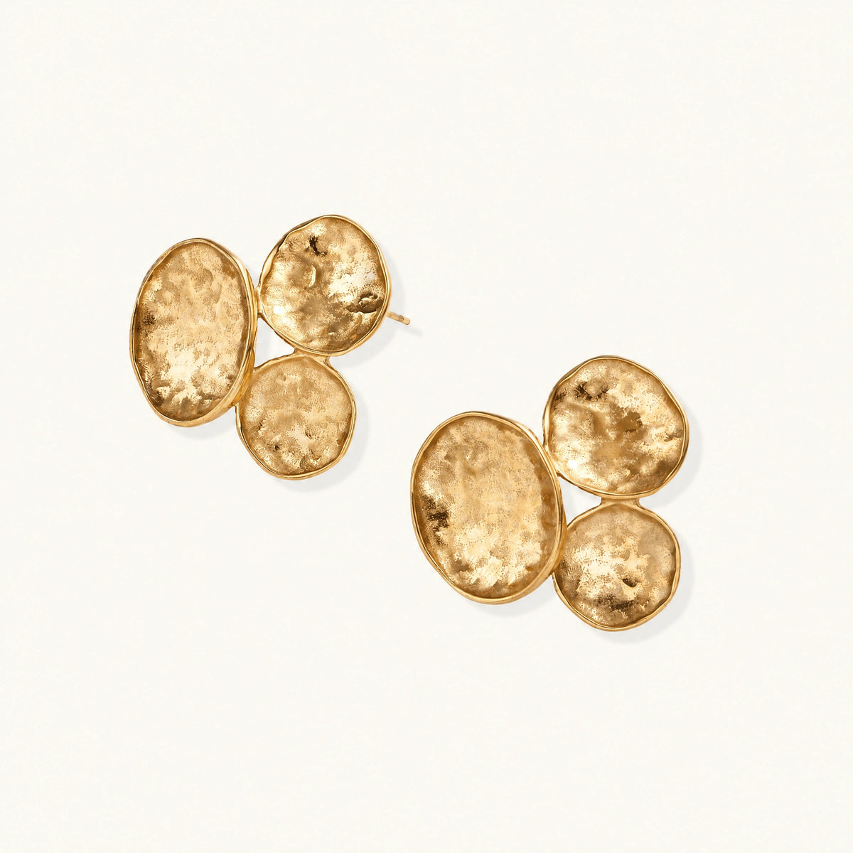 Three hammered gold discs clustered together forming organic statement earrings with textured surfaces