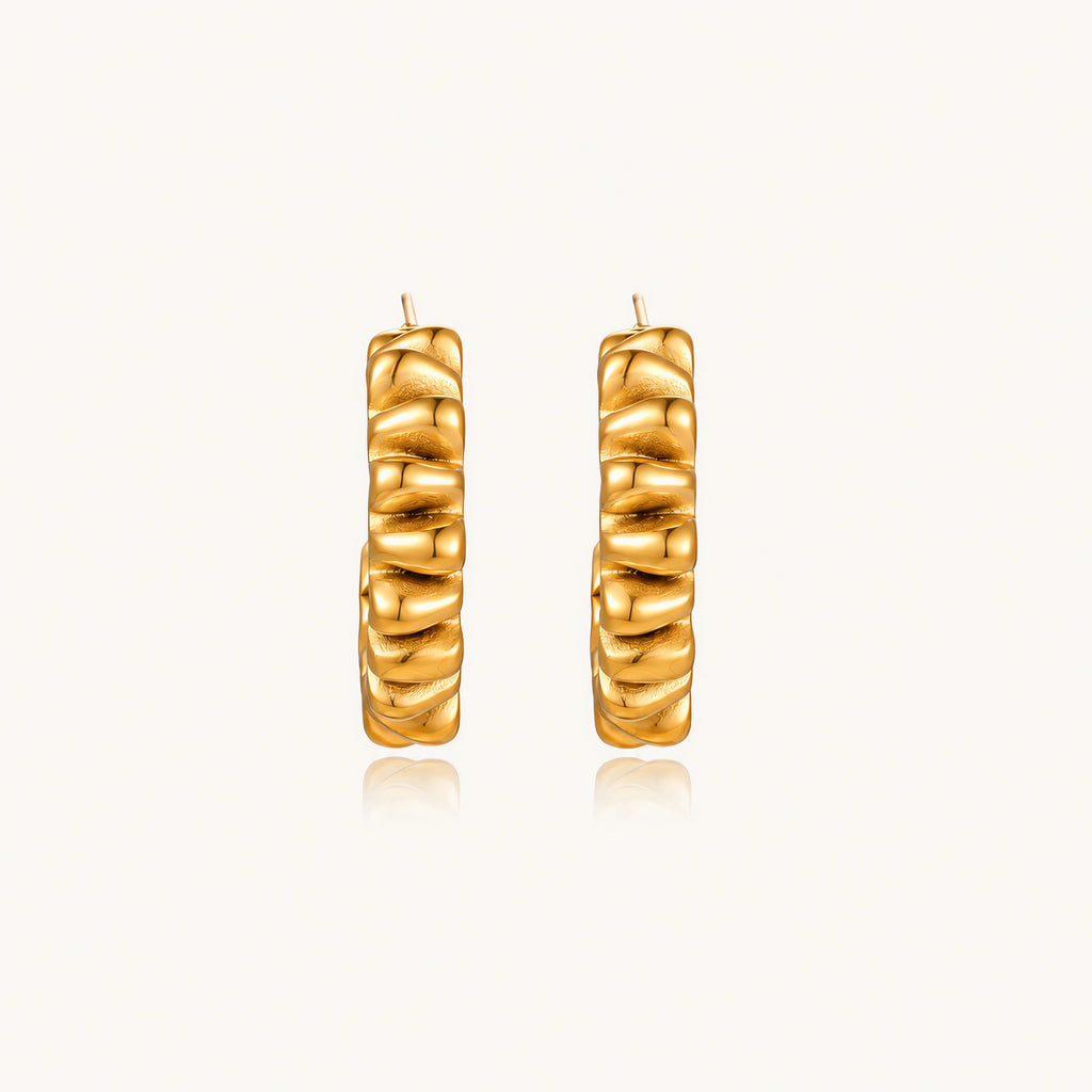 Sculptural gold-plated hoop earrings with continuous twisted spiral design on cream background