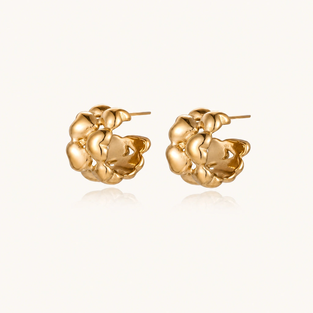 Close-up of gold-plated twisted rope huggie hoop earrings with brushed finish on white background.