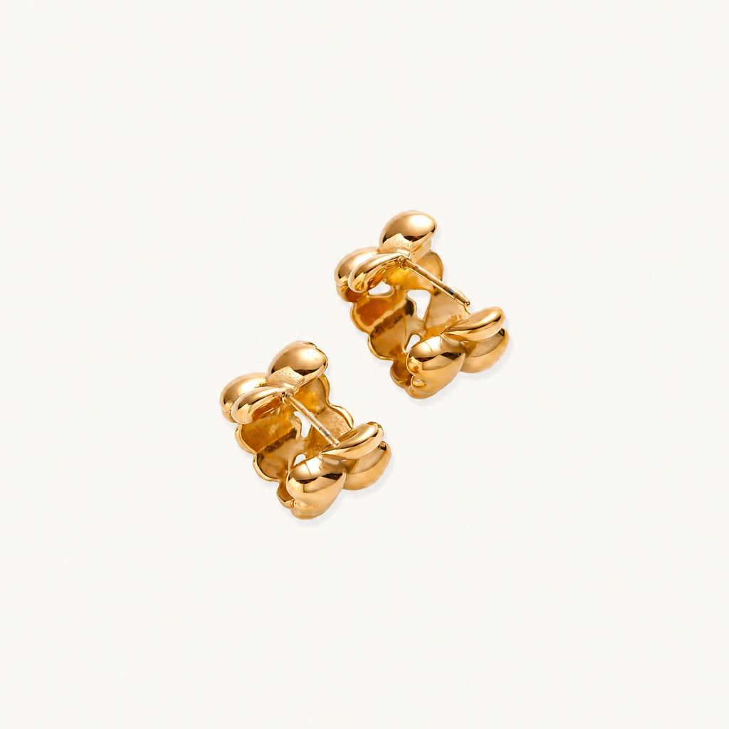 Close-up of gold-plated twisted rope huggie hoop earrings with brushed finish on white background.