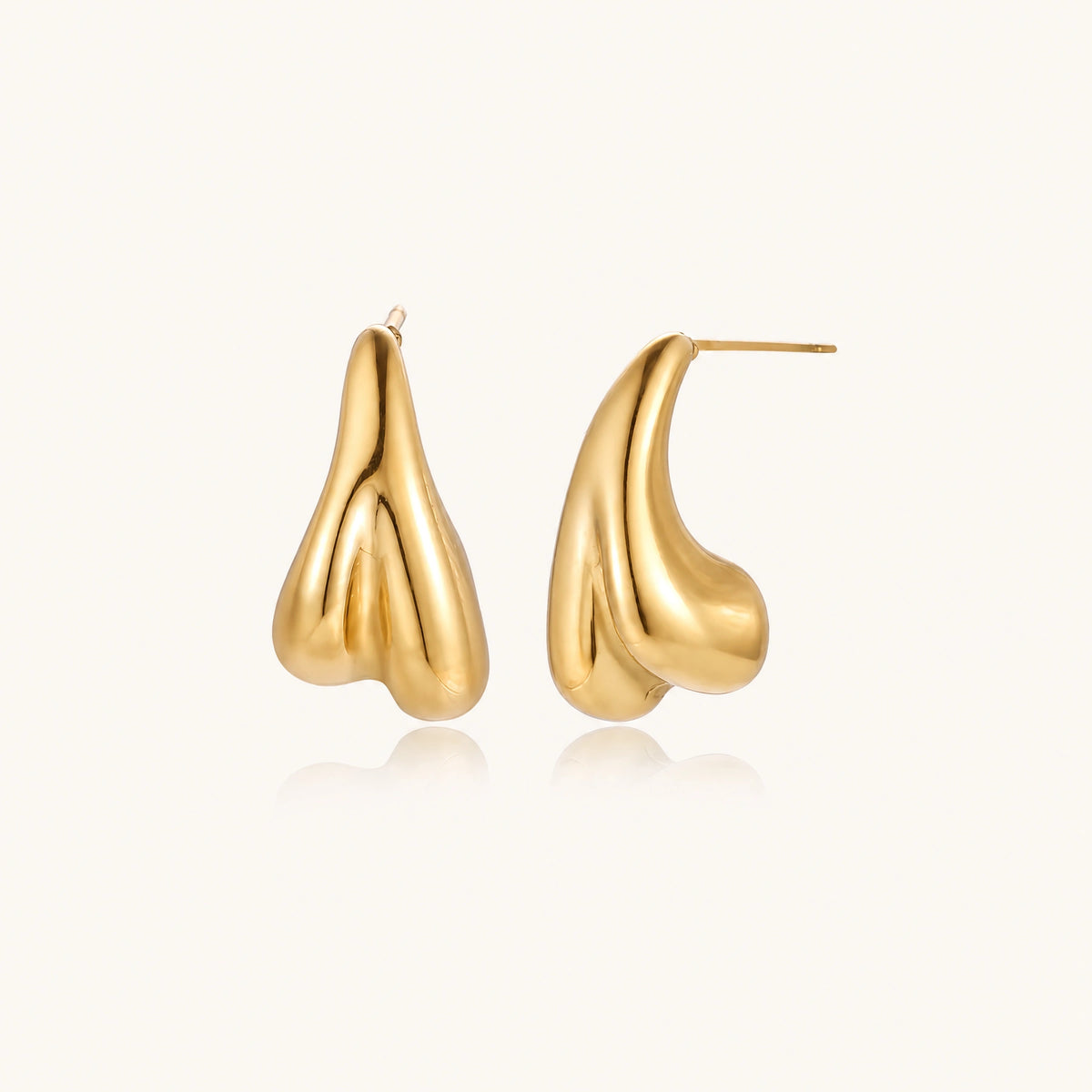 Organic sculptural gold stud earrings with fluid matte finish on cream background