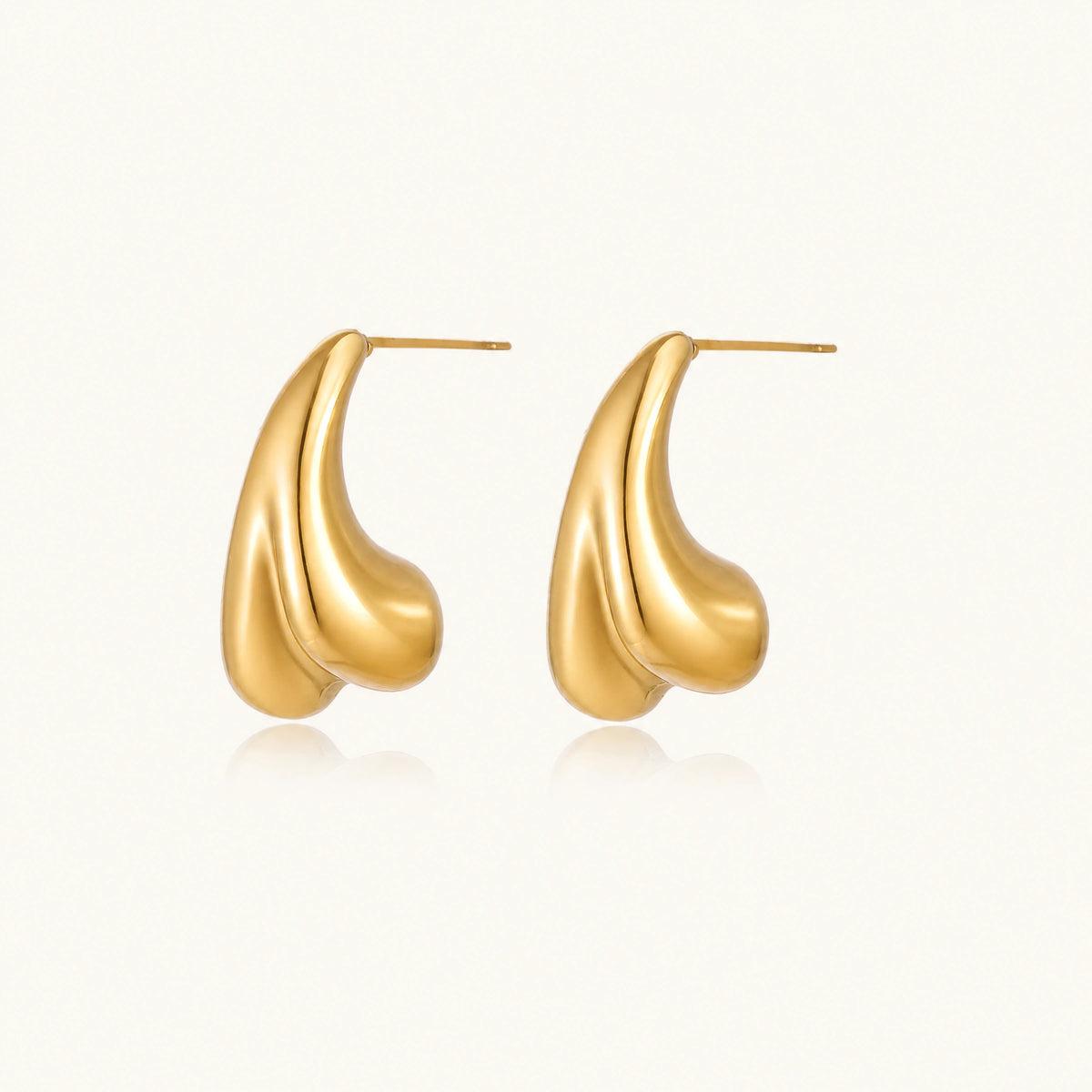 Organic sculptural gold stud earrings with fluid matte finish on cream background