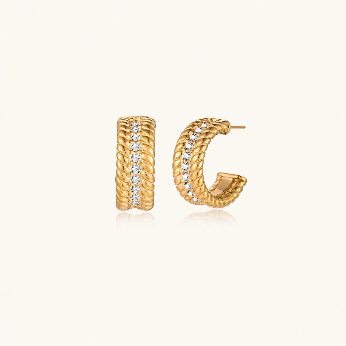 Textured gold huggie hoop earrings with raised ribbed rows creating dimensional sculptural design on cream background